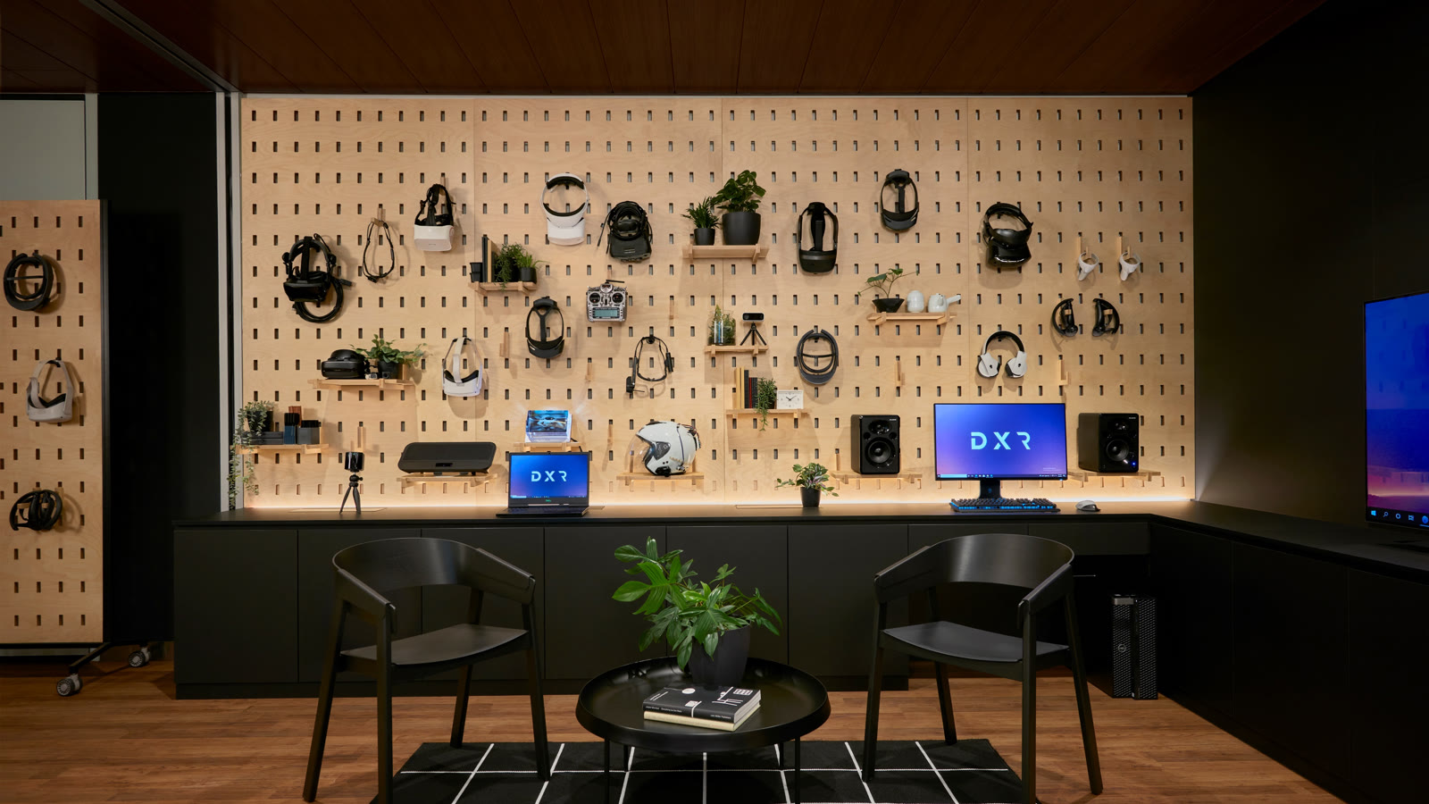 The full Dell XR Studios floor: a birch pegboard wall of headsets, the demo desk running the length of it, and the seating where customers actually sat.